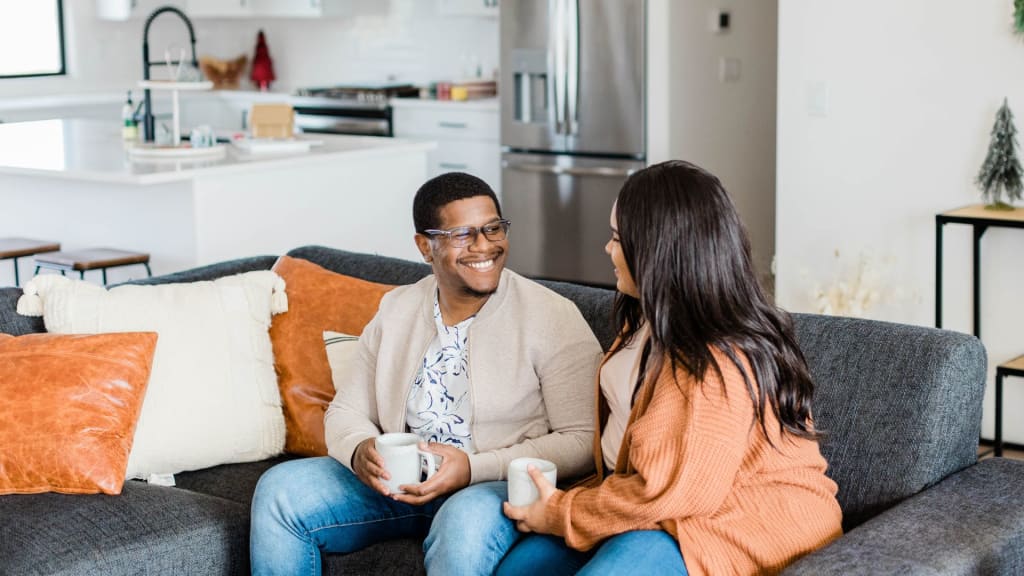 Happy Couple Sitting on Sofa Having Coffee
